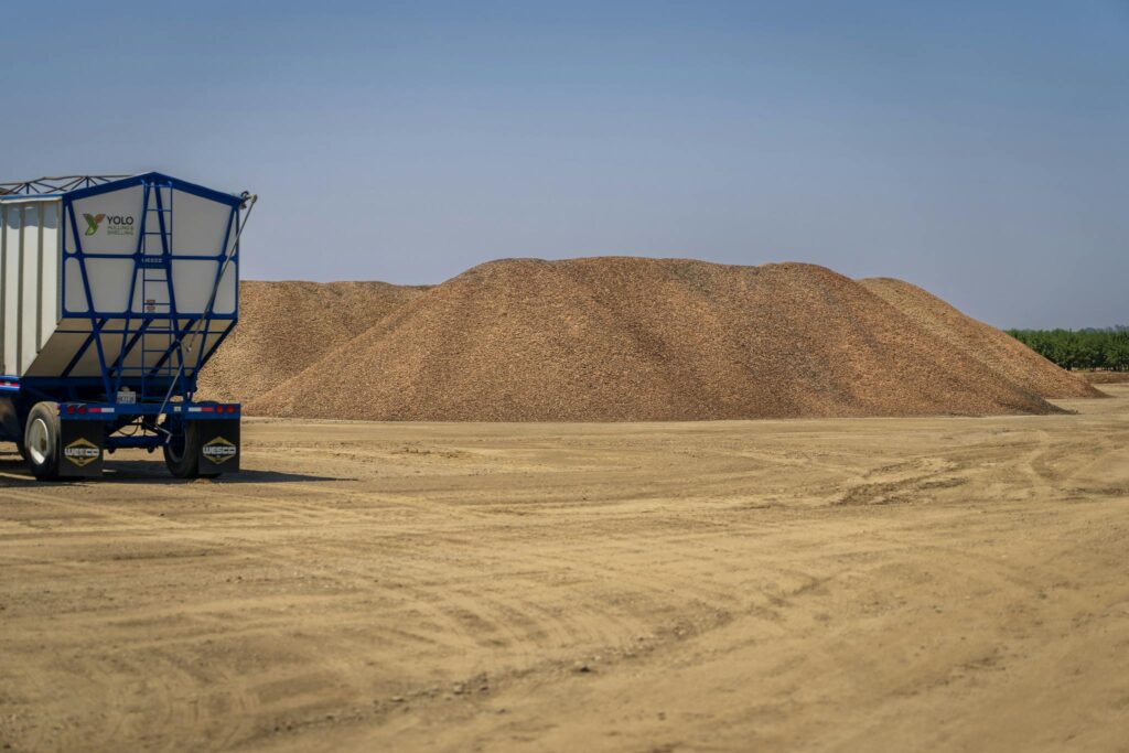 A barren landscape featuring sand piles and a transportation truck under a clear sky.